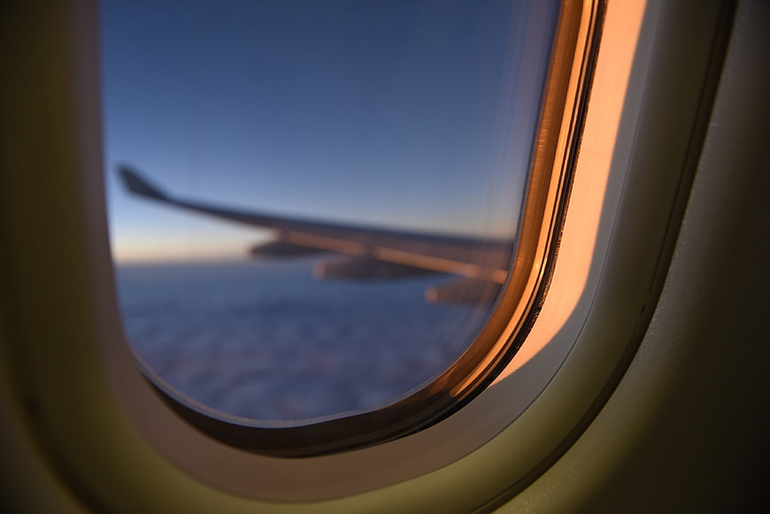 Airplane wing seen through a cabin window at sunset.